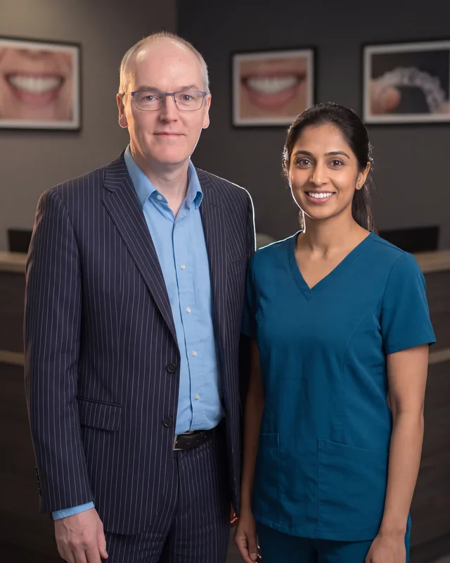 Carl Fox with a dentist in a UK dental practice reception beside an Invisalign print